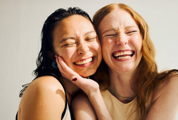 Why Asian Skin Ages Differently 2 Two women smiling with eyes closed, leaning heads together in a joyful moment.